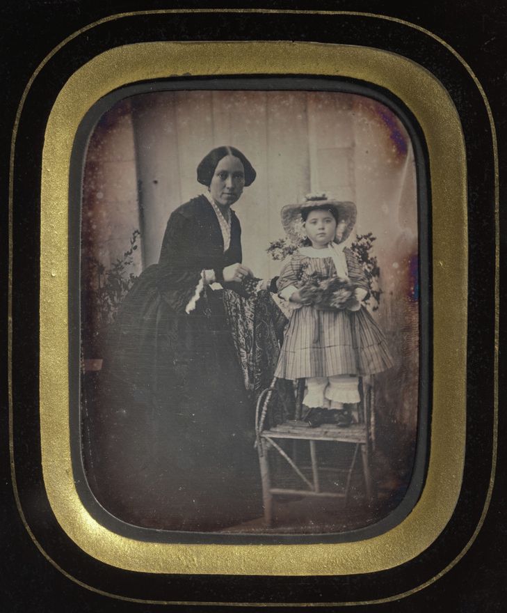 Child Standing on a Chair Holding Flowers, with Mother by Unknown artist